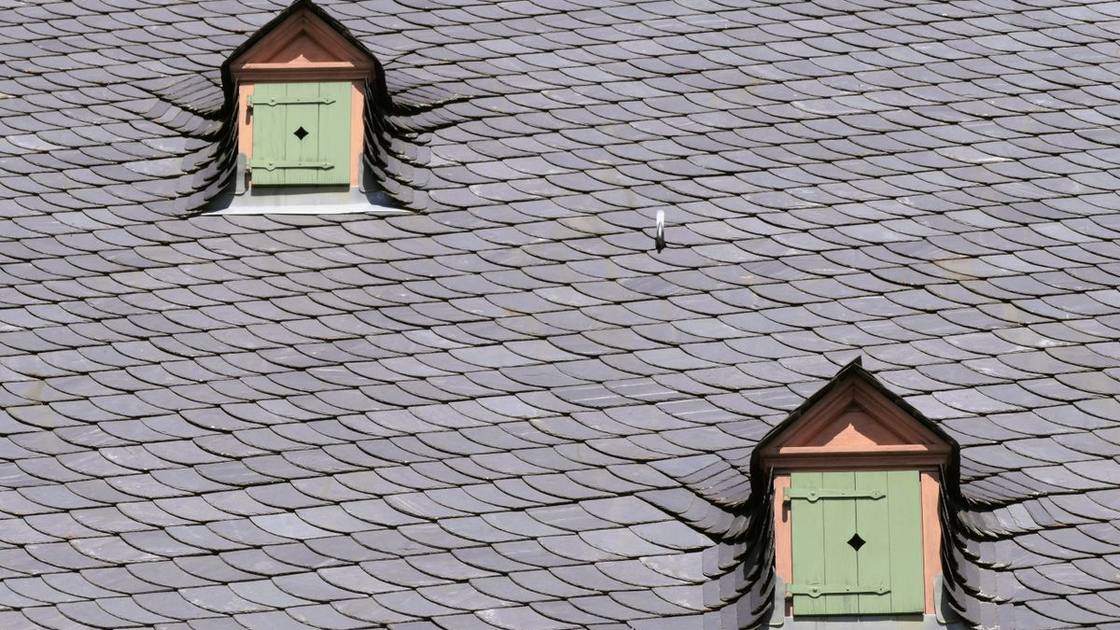 Toit en ardoise avec deux lucarnes à volets verts, couverture typique en Normandie