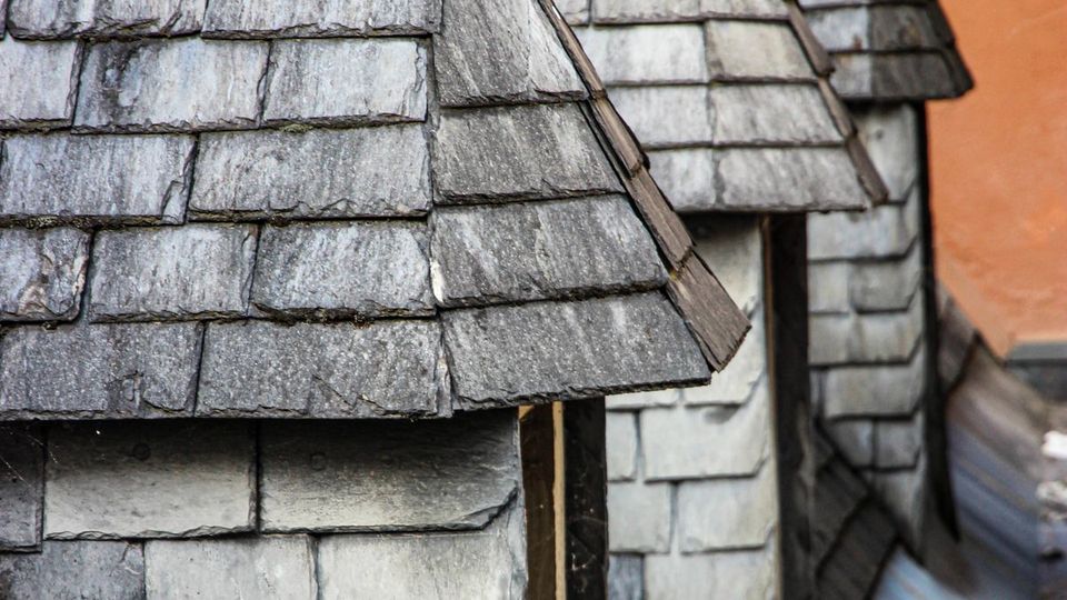 Toits en ardoise serrés d'un centre ancien normand sous un ciel gris